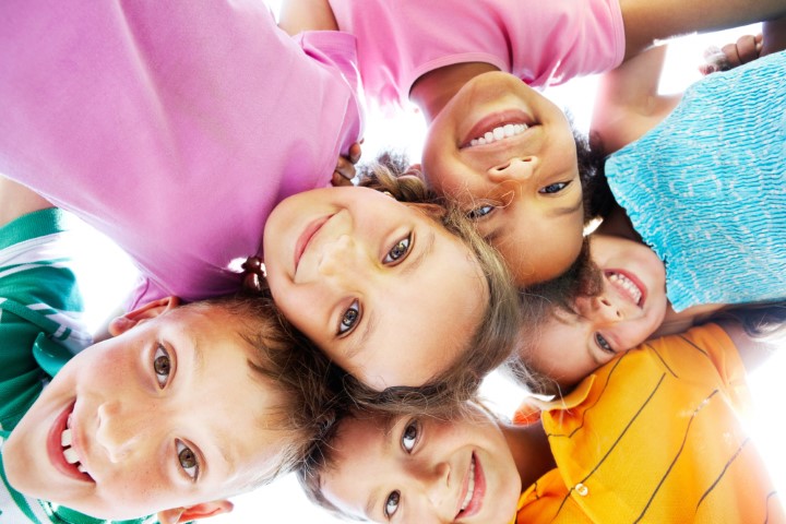 Below view of happy children embracing each other and smiling at camera